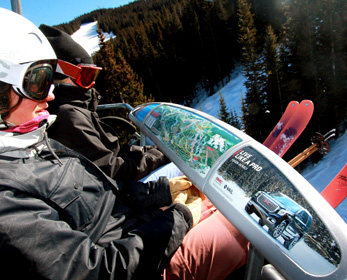 Skiers looking at the mountain map next to a GMC ad