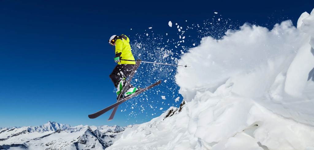 Man skiing off mountain; winter sports.