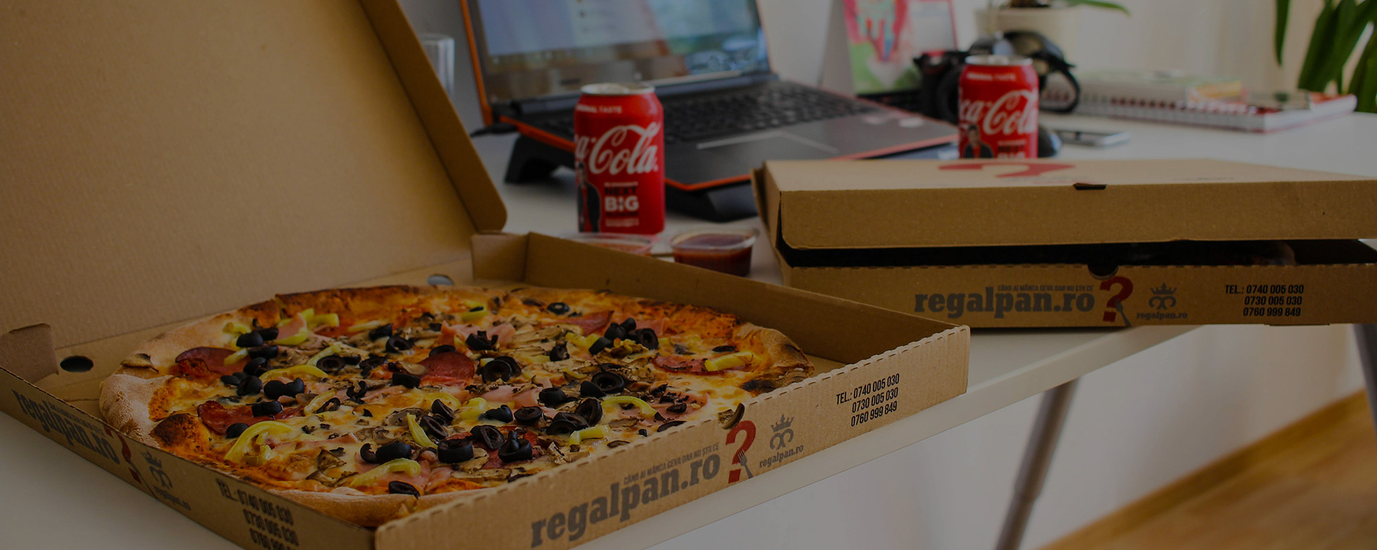 Pizza boxes with advertisements on them placed on a desk