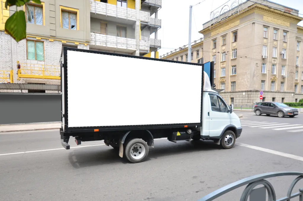 Commercial truck with empty mockup banner on a van. Mobile advertising truck in an urban environment.