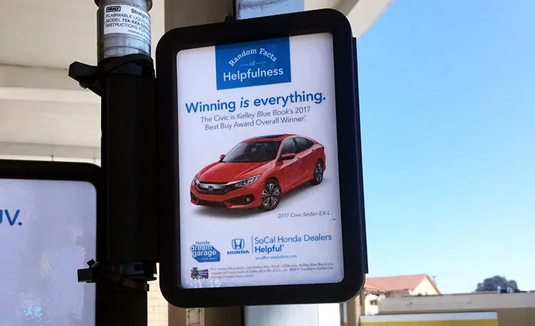 Honda ad on the hose of a gas pump that displays a red Honda Civic