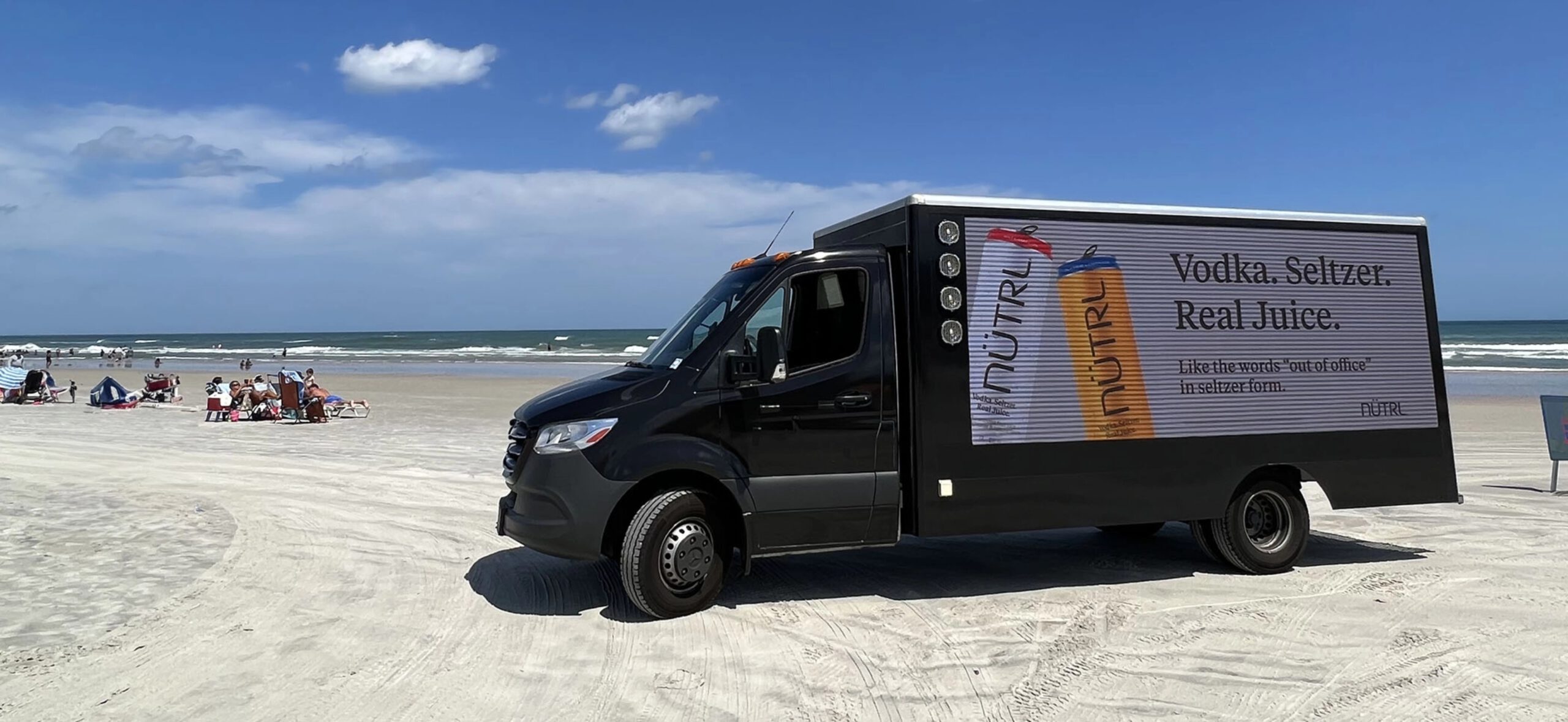 Nutrl van-side advertisement being driven across a beach