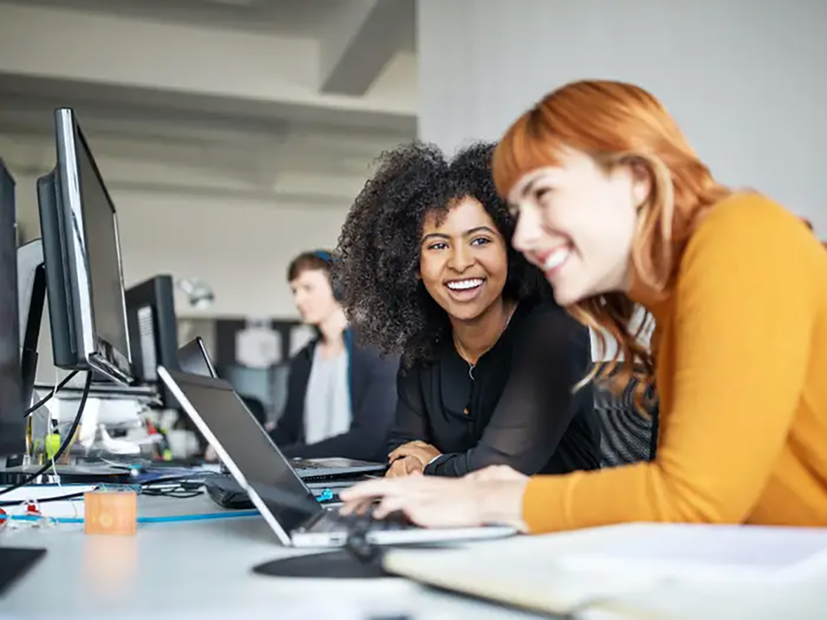 Two women working together on computers at a desk