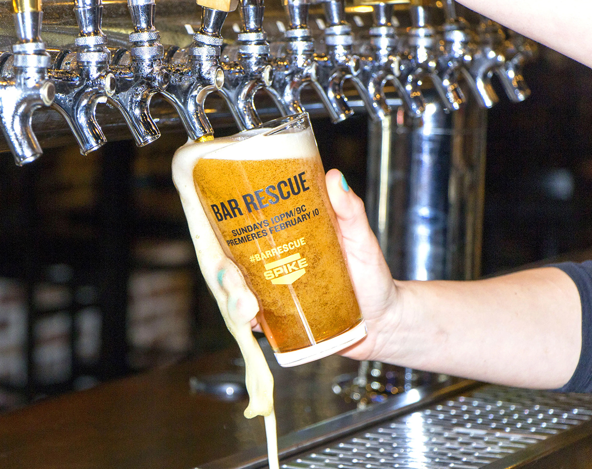 Bartender filling a beer glass with a Bar Rescue ad on it