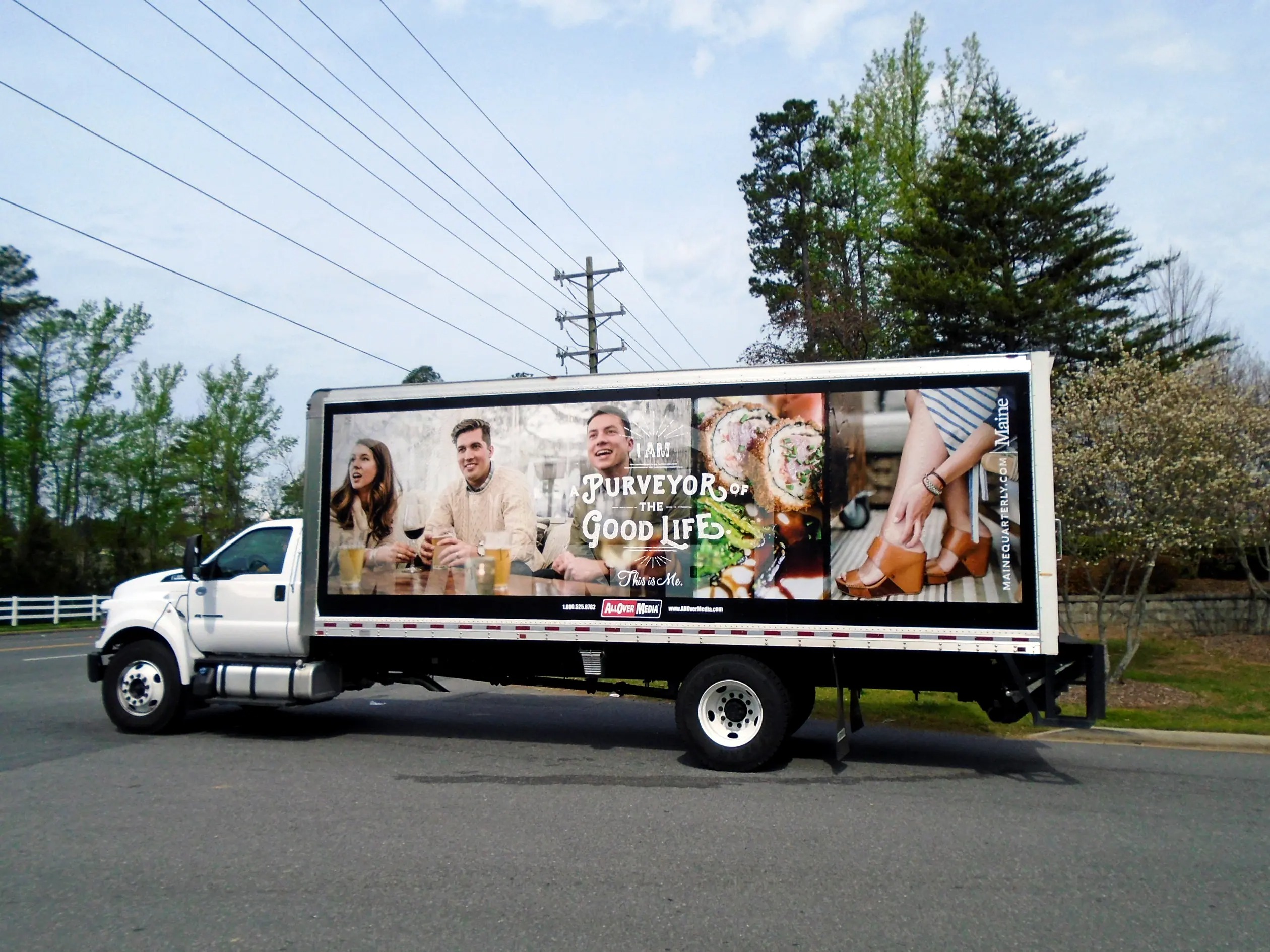 Tourism truck-side ad for Maine Quarterly being driven in a rural area