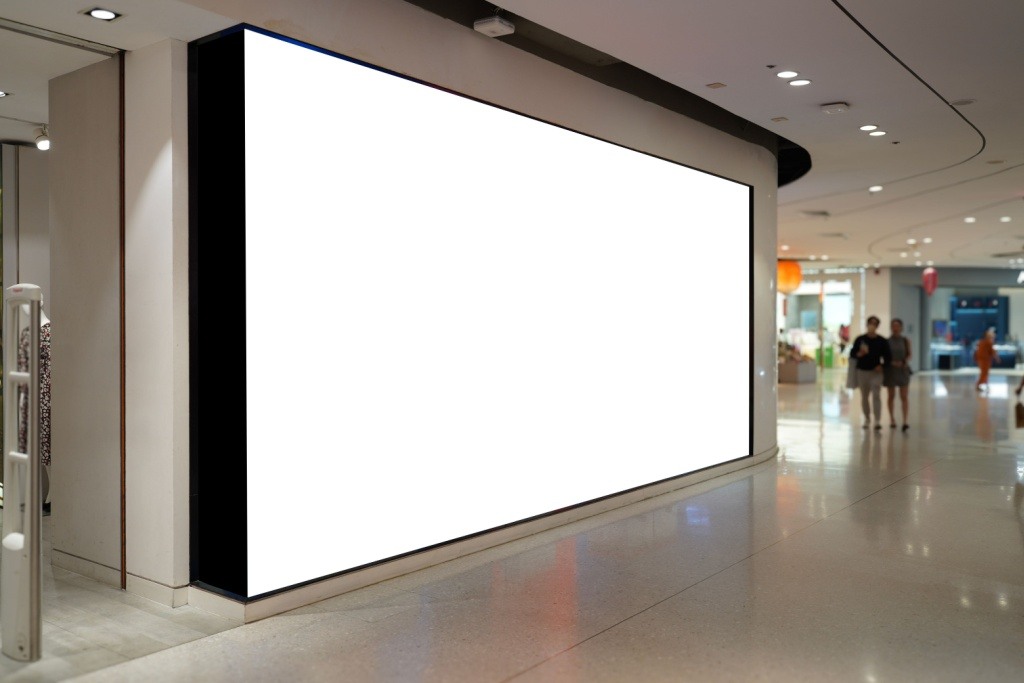 A prime retail location beckons with a large empty billboard in shopping mall