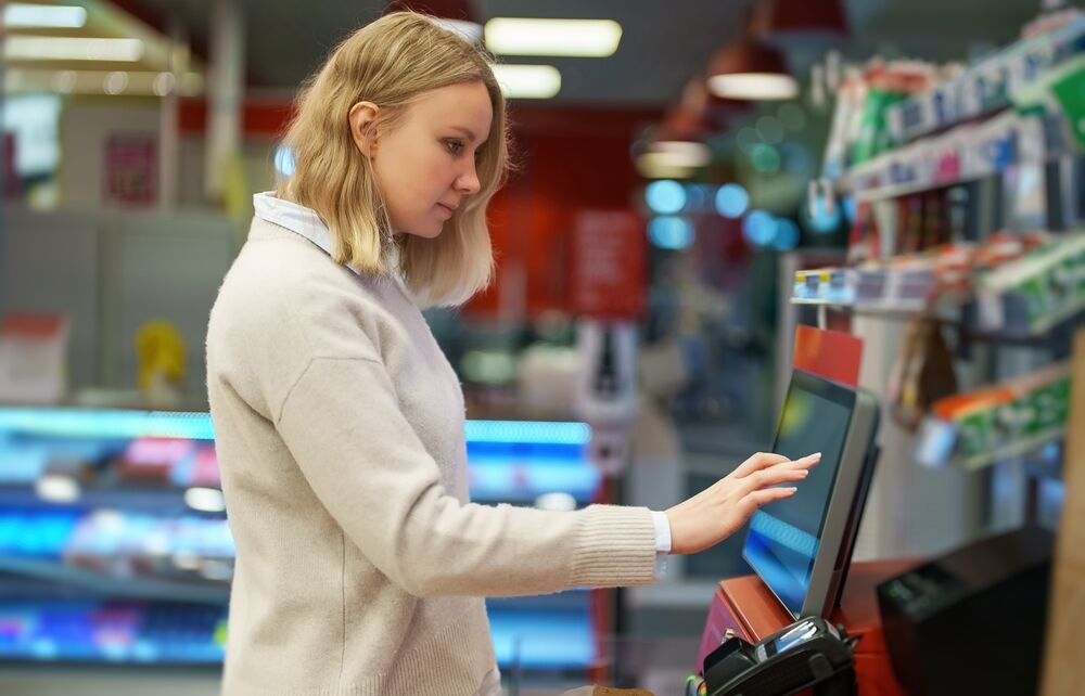 Woman pays at self-checkouts in convenience store