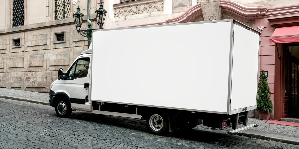 Delivery truck with is parked at urban street with stone road and sidewalk